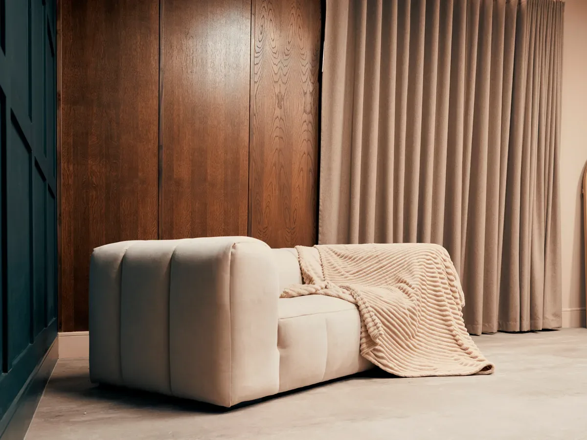 Boucle sofa against warm wood panelling and taupe curtains in Cover Story