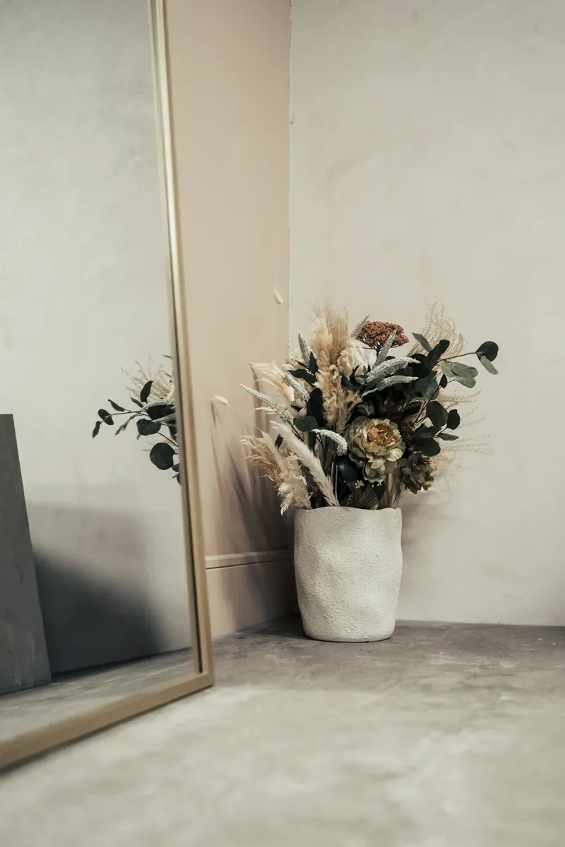 Arched gold mirror and dried flowers against warm plaster in Cover Story